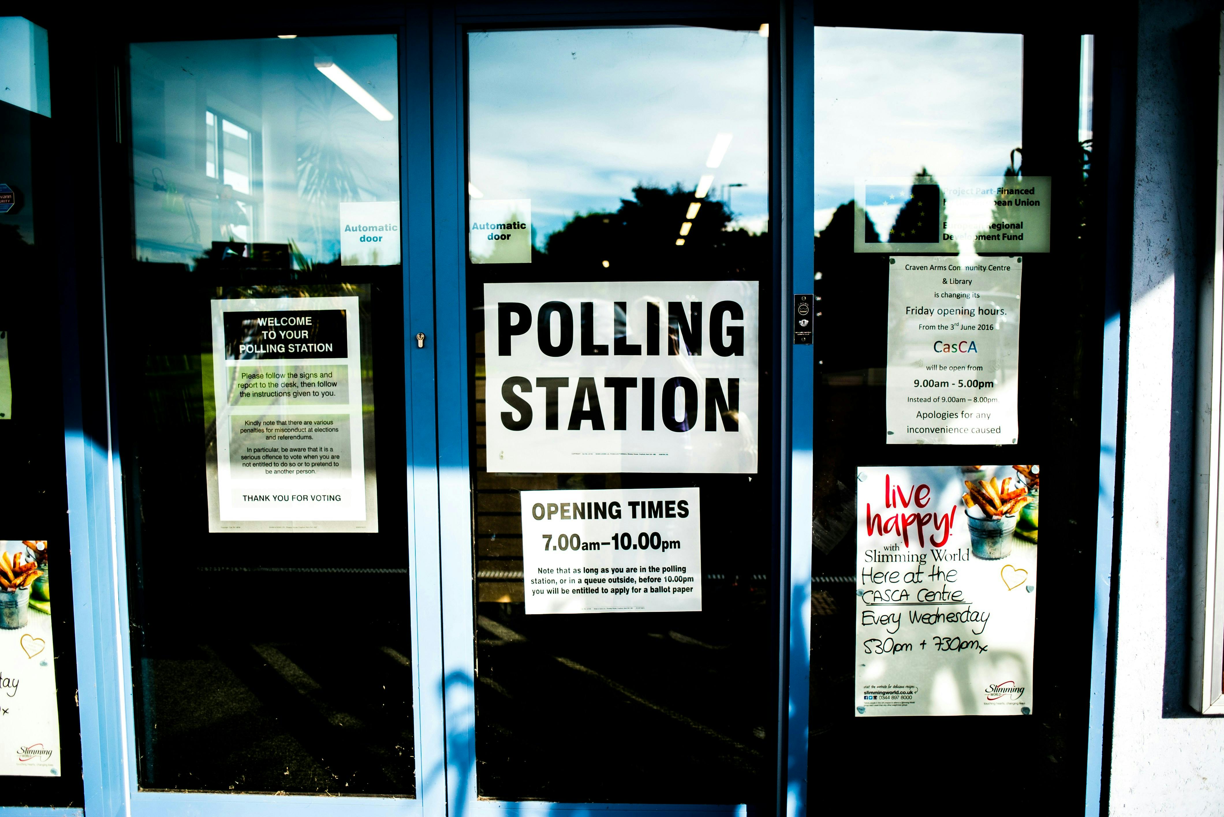 A door with a sign that says, "Polling Station. Opening Times 7:00 AM to 10:00 PM."