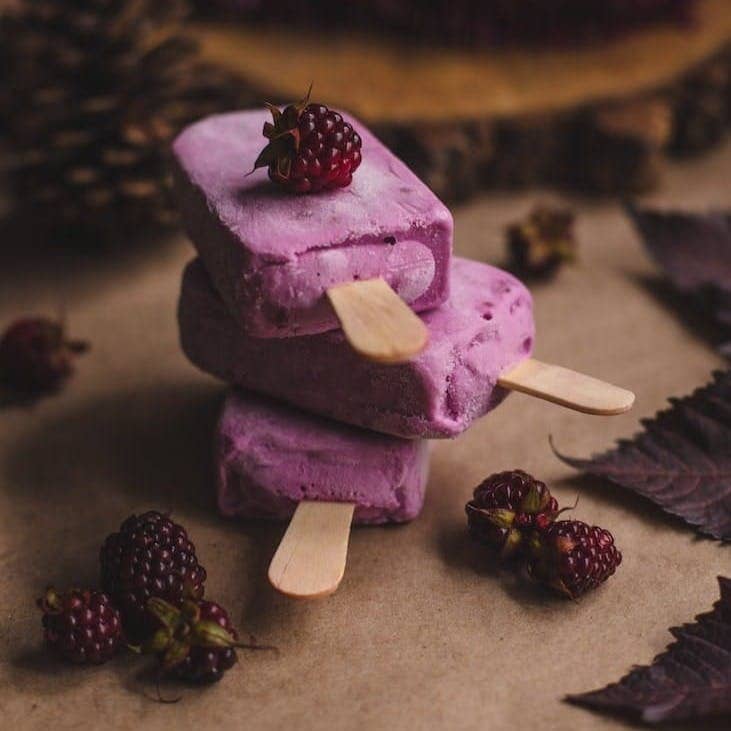 selective focus photography of thee purple ice pops near pine cones