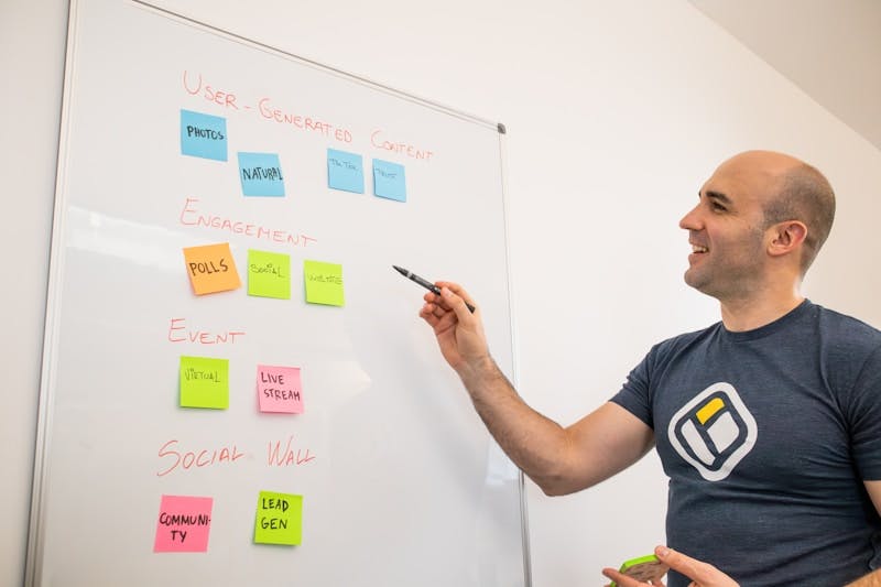 a man writing on a white board with sticky notes on it