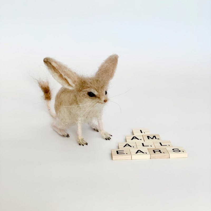 A small rabbit standing next to a scrabble of scrabble letters