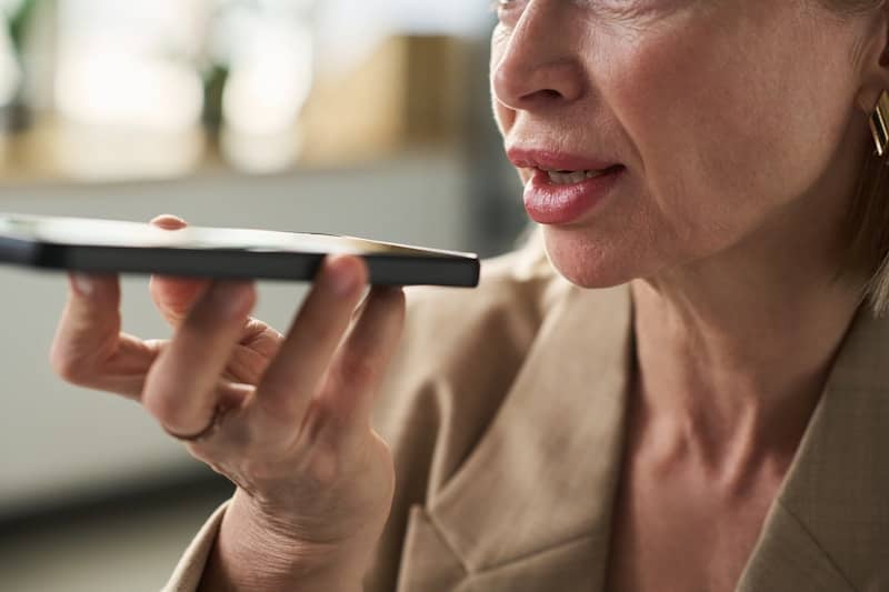 Woman is holding a phone to her mouth.