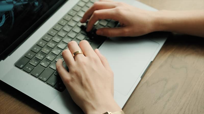 A woman is typing on a laptop computer