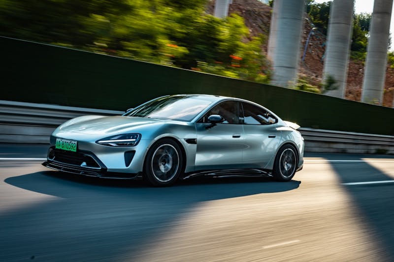 A silver sports car driving down a road