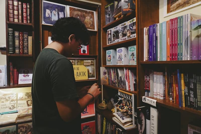 A person browses bookshelves in a cozy bookstore.
