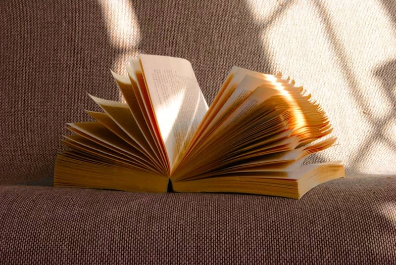 An open book lies on a soft surface.