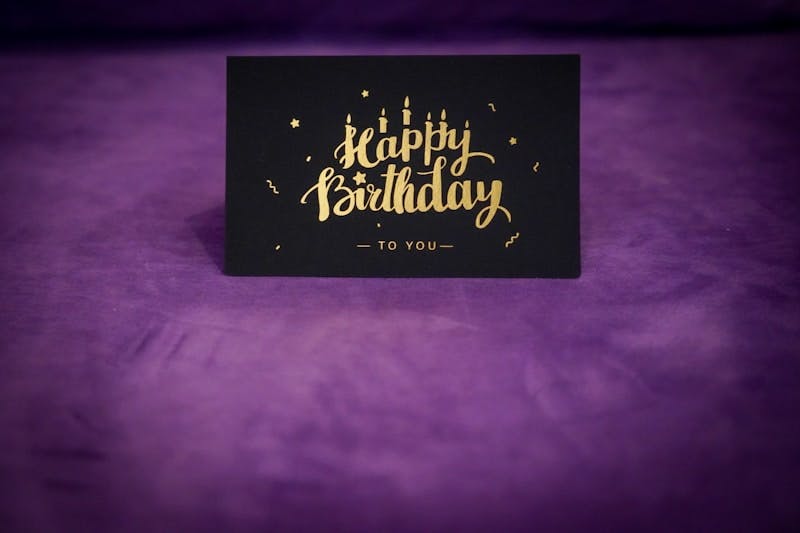 A black and gold happy birthday card on a purple background