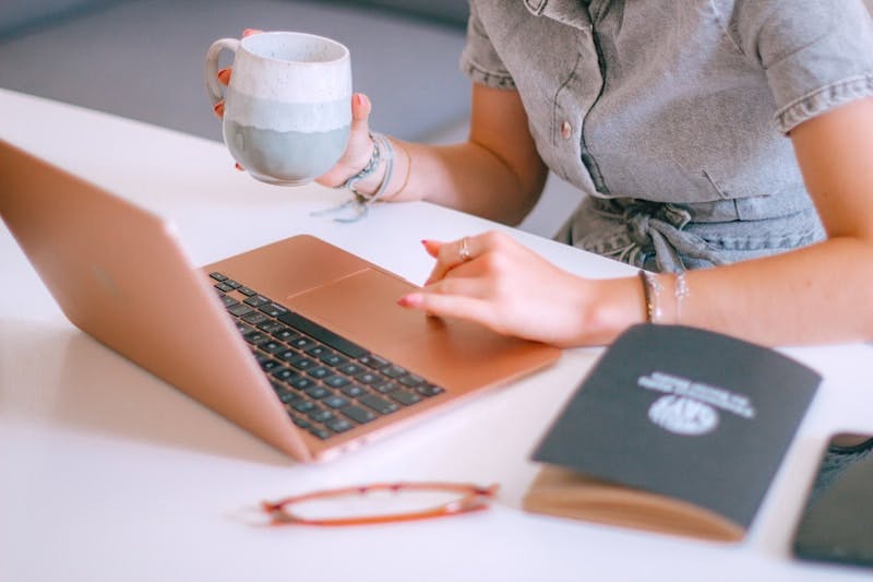 A woman sitting at a table with a laptop and a cup of coffee