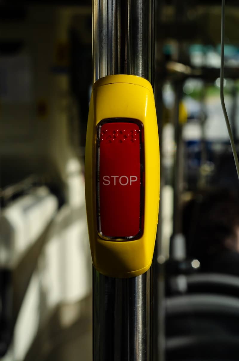 A yellow and red stop button on a metal pole