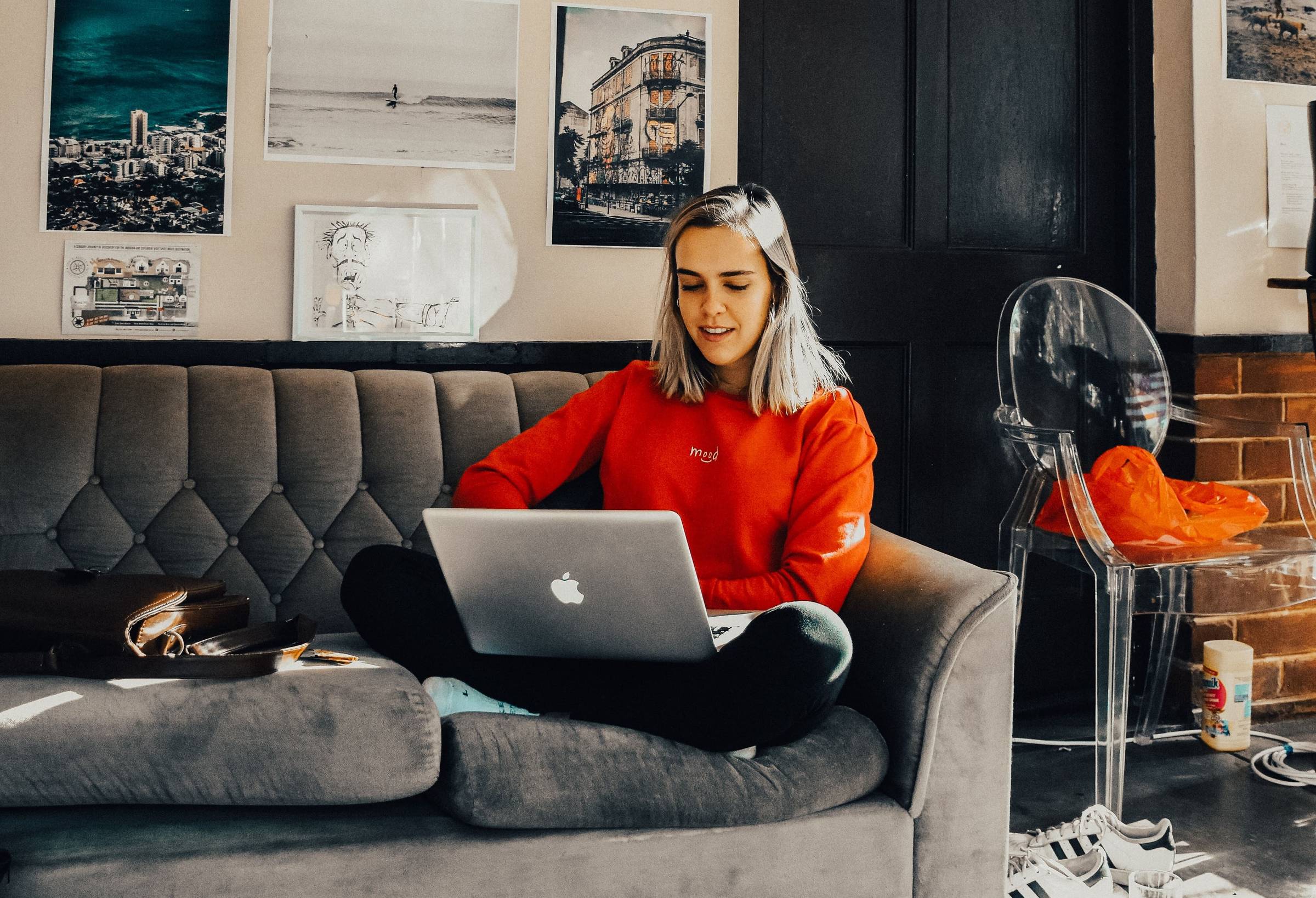 A blonde woman sitting on a couch with a laptop computer