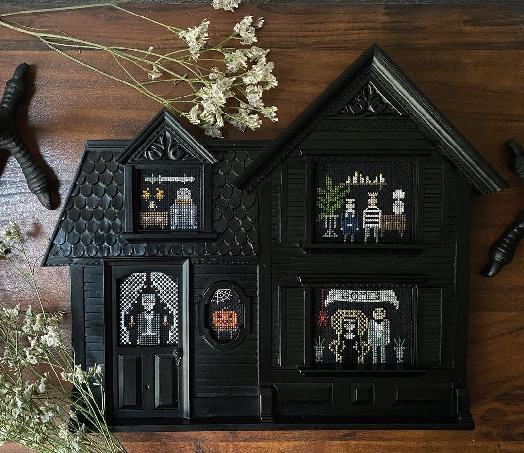 Decorative house filled with cross stitched portraits of the Addams Family 