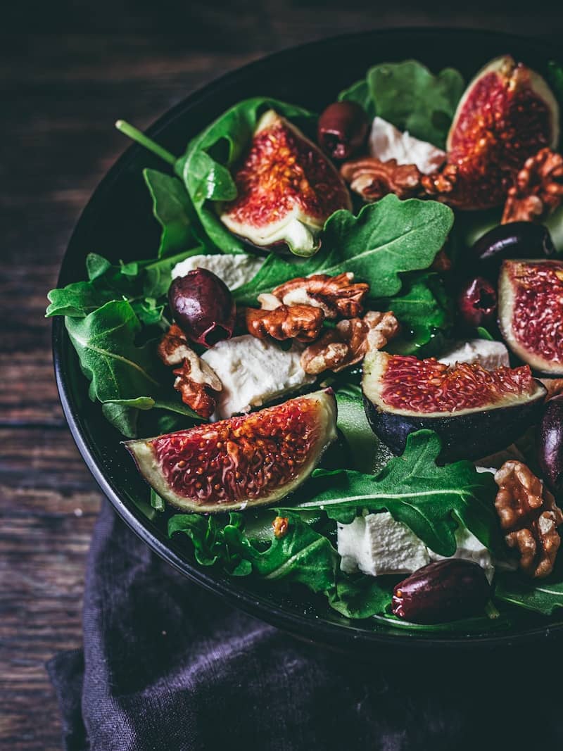 A salad with figs, nuts, and greens in a bowl