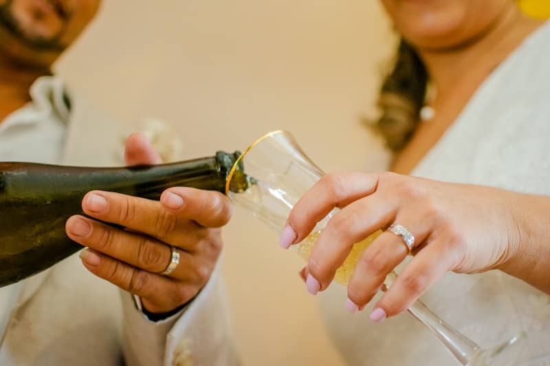 a bride and groom holding a bottle of champagne