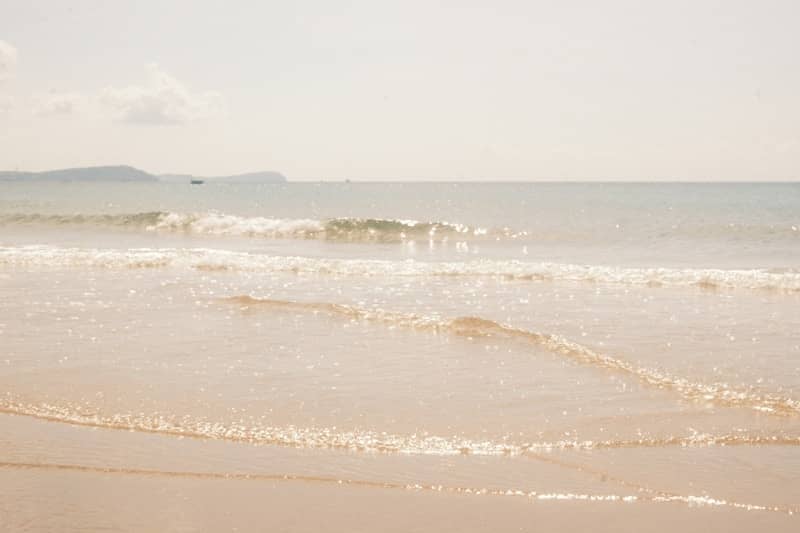 Sandy beach with gentle ocean waves and distant land.