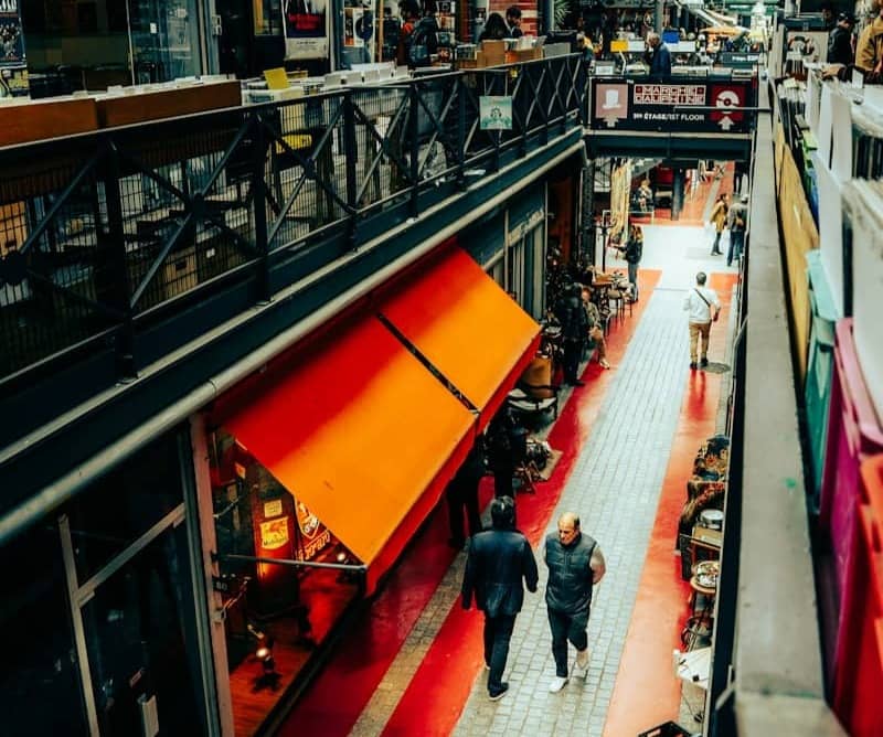 People walking through a busy indoor market with red accents.