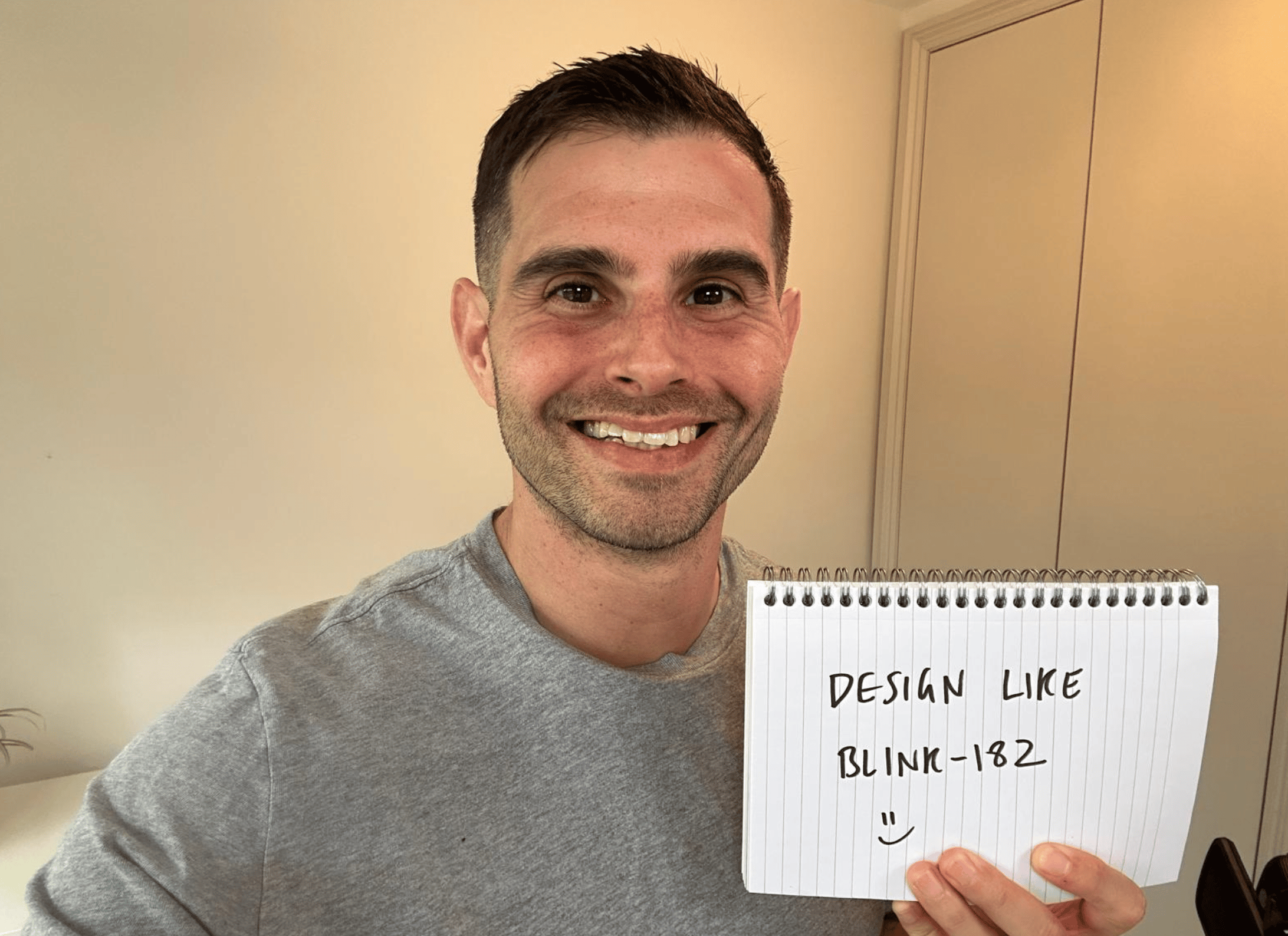 Me holding a sign that says "Design like Blink-182"