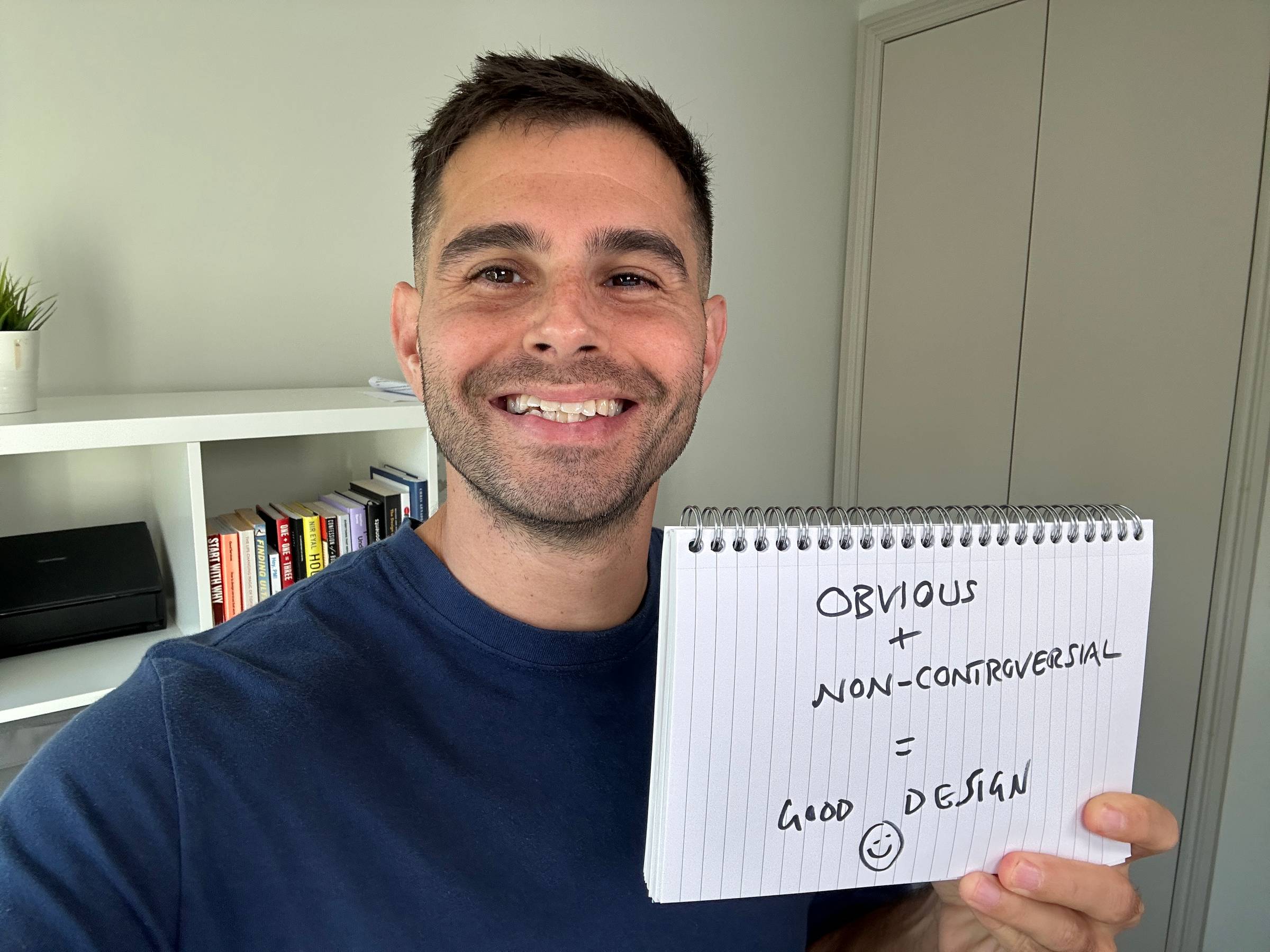 Me holding a sign saying: Obvious + Non-controversial = good design