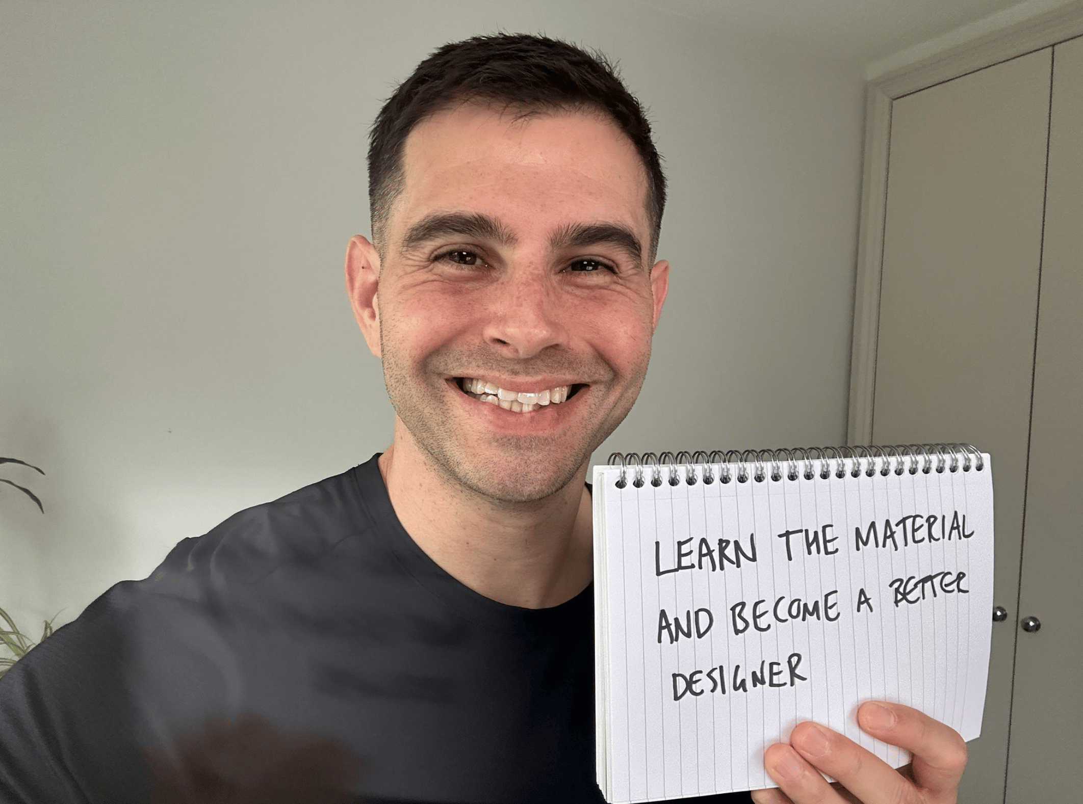 Me holding a sign saying learn the material and become a better designer. 