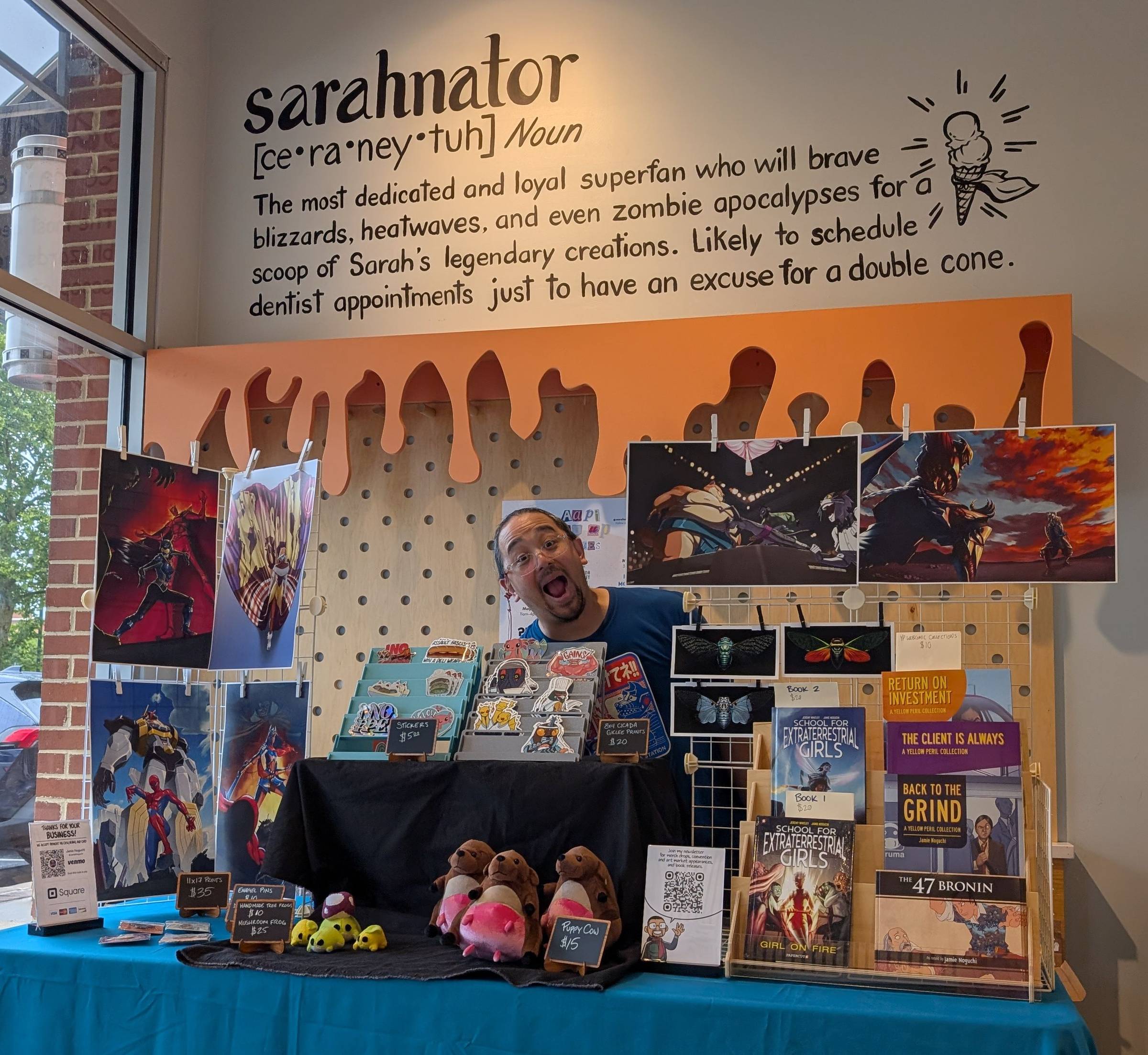 A photo of me behind my convention setup. Above me on the wall behind me is written "sarahnator [ce*ra*ney*tuh] Noun. The most dedicated and loyal superfan who will brave blizzards, heatwaves, and even zombie apocalypses for a scoop of Sarah's legendary c