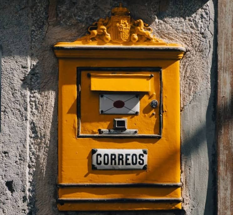 Yellow vintage mailbox mounted on a stone wall.