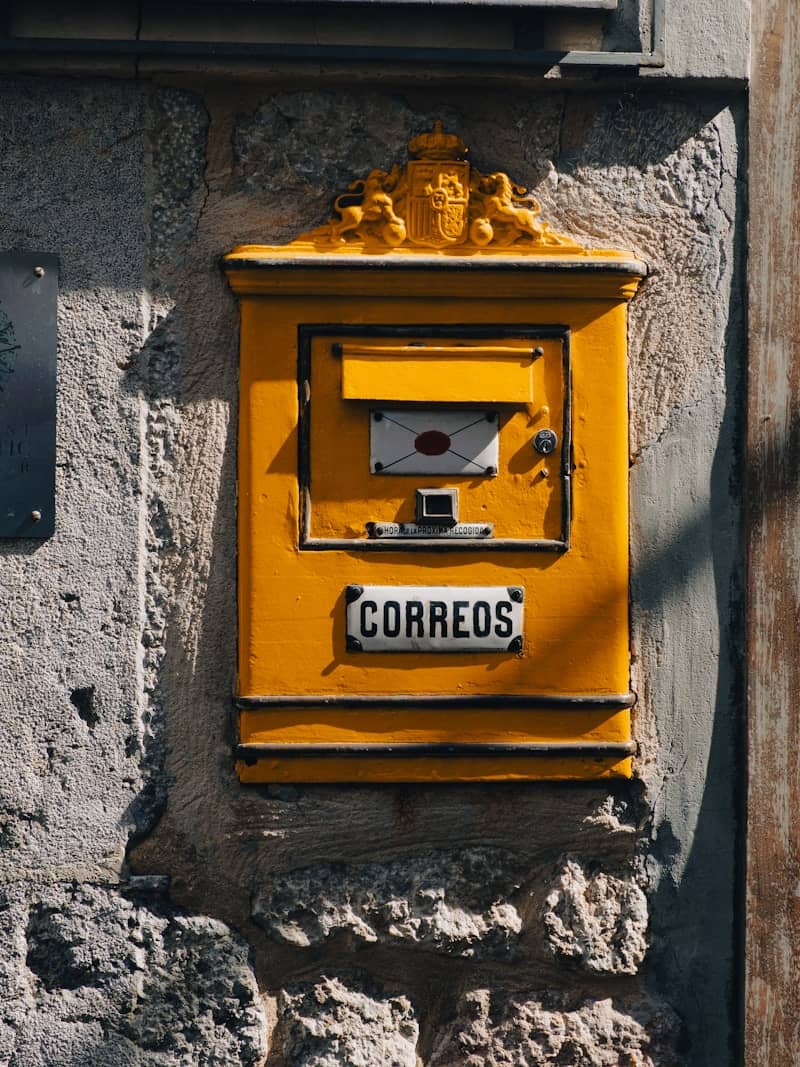 Yellow vintage mailbox mounted on a stone wall.