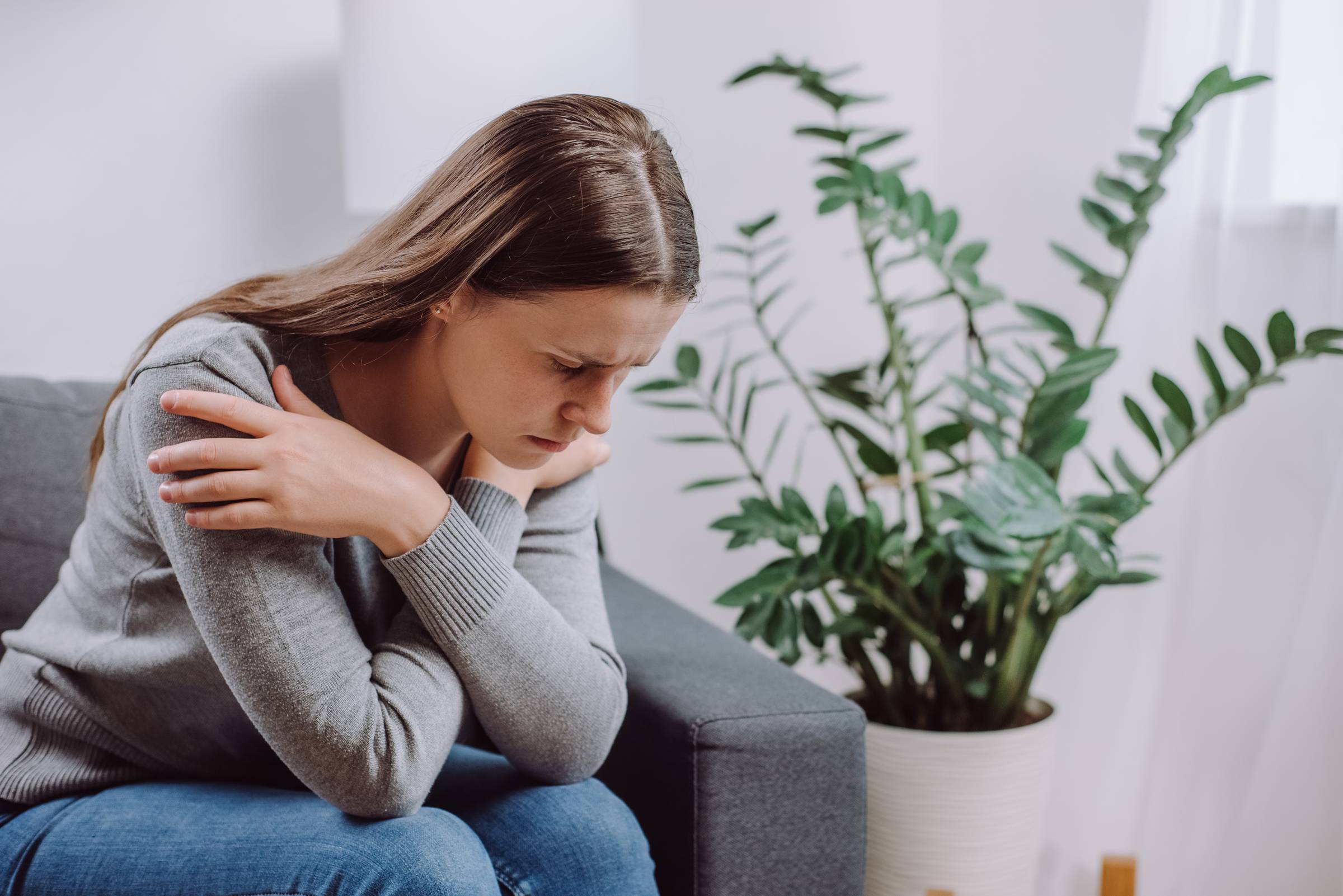 Frustrated unhappy young female sitting on couch at home alone, thinking about personal problem, break up with boyfriend or divorce, need psychological help, girl feeling lonely and depressed