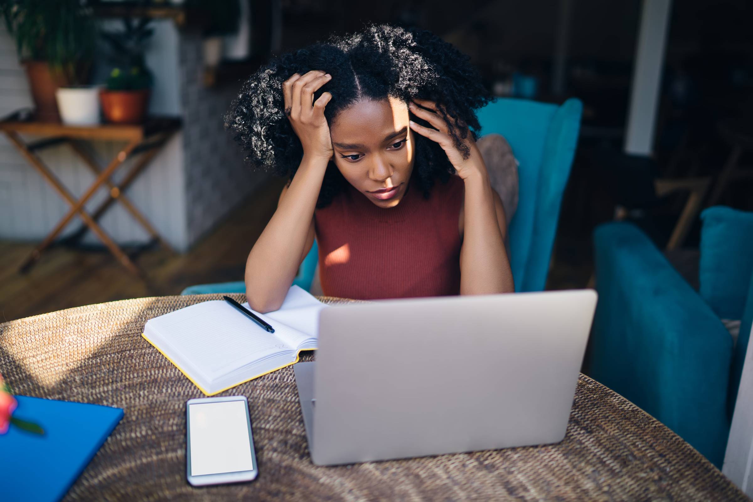 African American stressed female looking at laptop in cafe