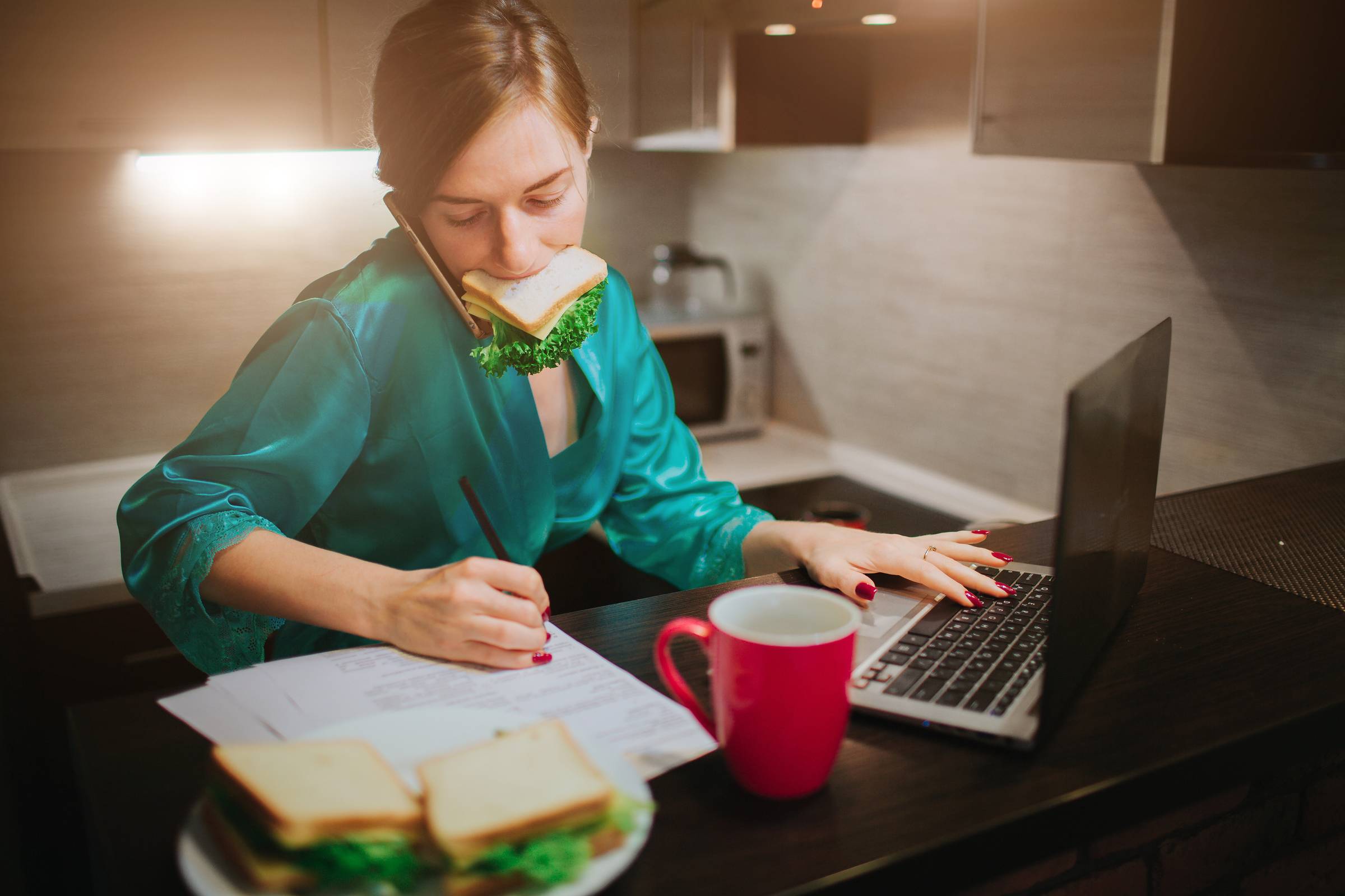 Busy woman eating, drinking coffee, talking on the phone, working on a laptop at the same time. Businesswoman doing multiple tasks. Multitasking business person. Freelancer works at night.