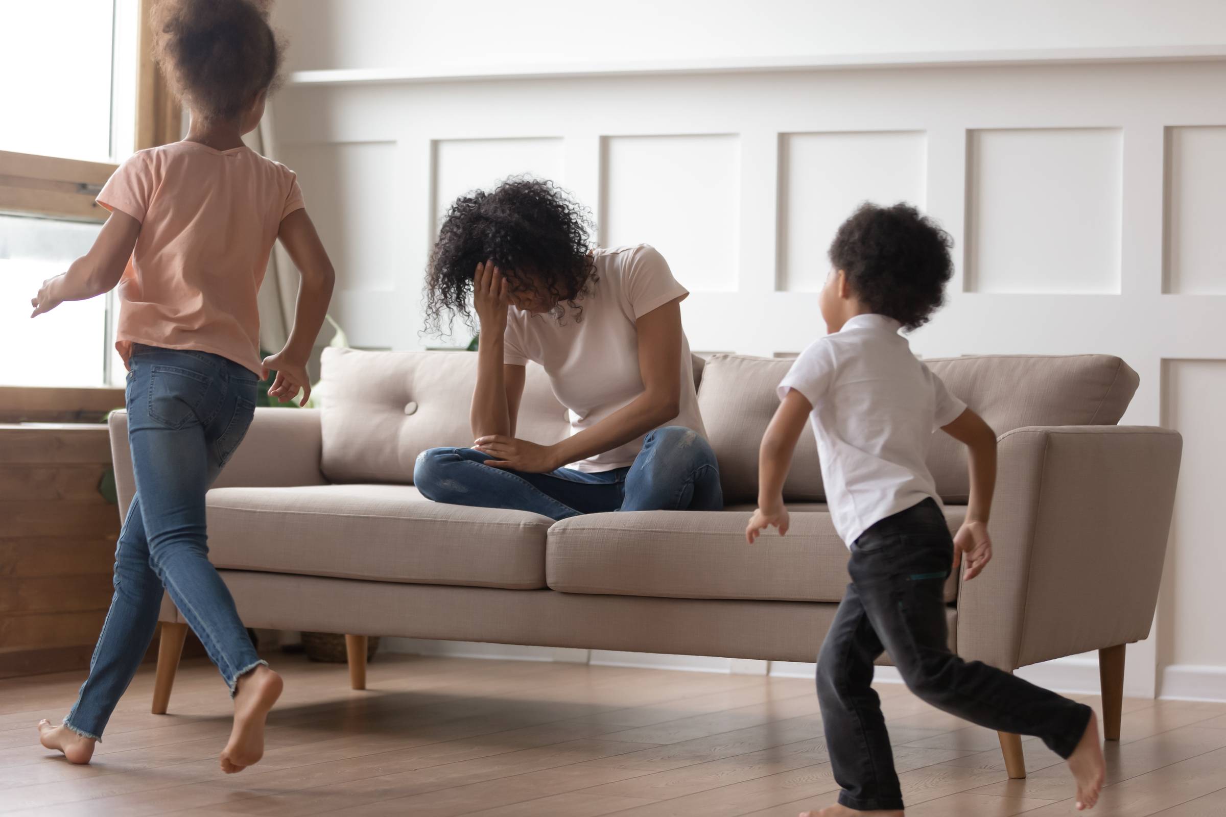Black mother sit on couch can't handle with noisy kids