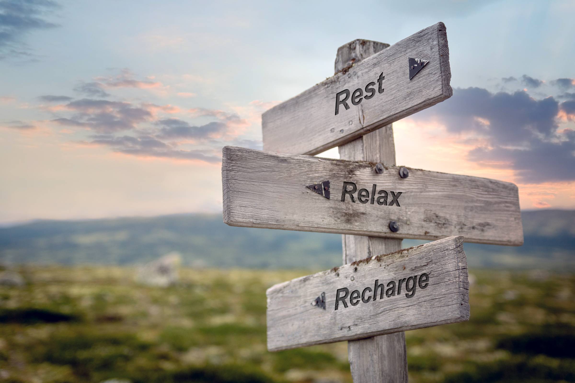 rest relax recharge text on wooden sign outdoors.