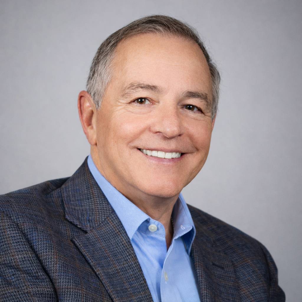 Sal Conino's professional headshot. He is smiling at the camera, wearing a navy blazer with a subtle plaid pattern and a blue button-down shirt, top button open.