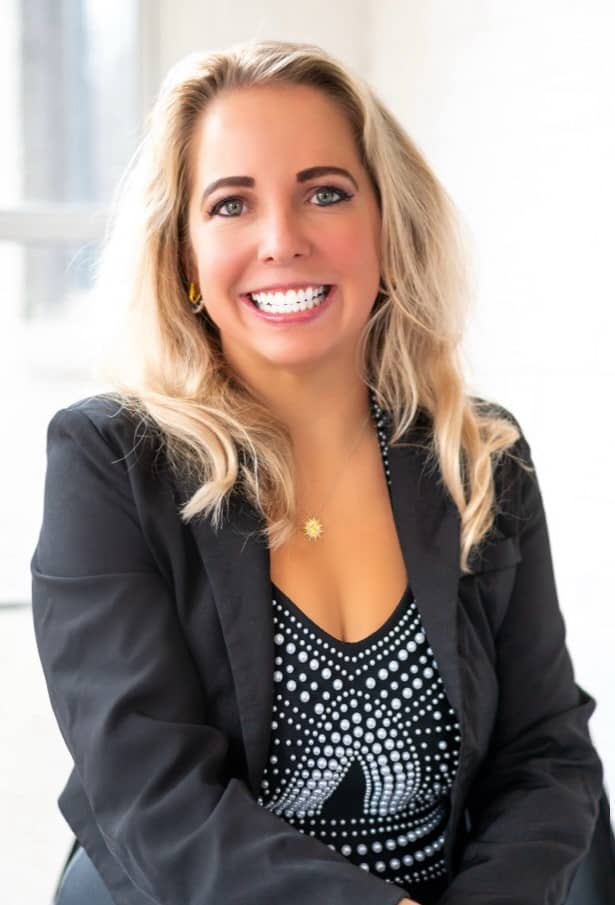 Brandi Gerew flashes a dazzling smile while wearing a black blazer and black and white blouse