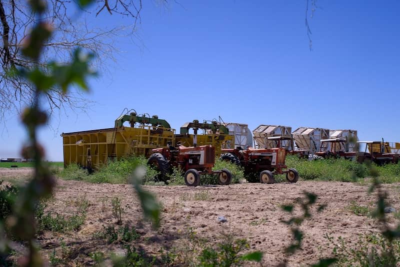 Two tractors parked in a field with farm equipment.