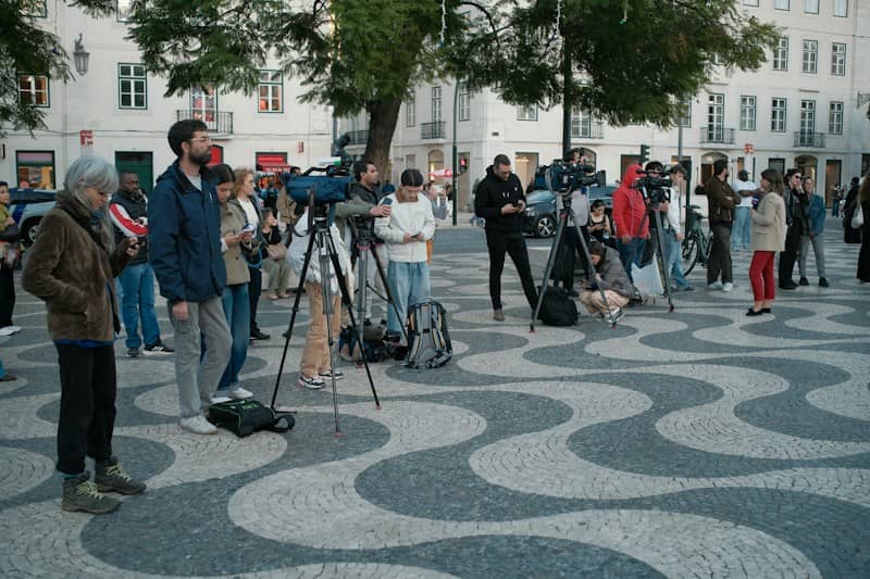 Television crews and journalists on the black and white patterned calçada of Rossio Square in Lisbon