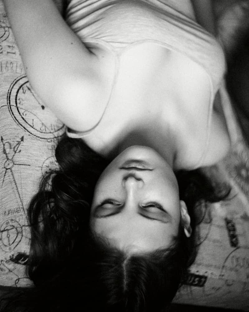 A person with dark hair lying on a patterned fabric surface
