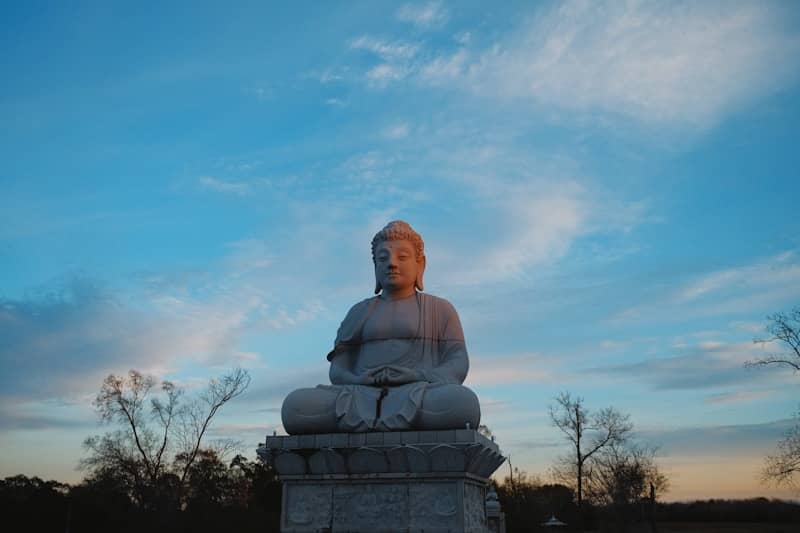 Stone buddha statue against a vibrant twilight sky.