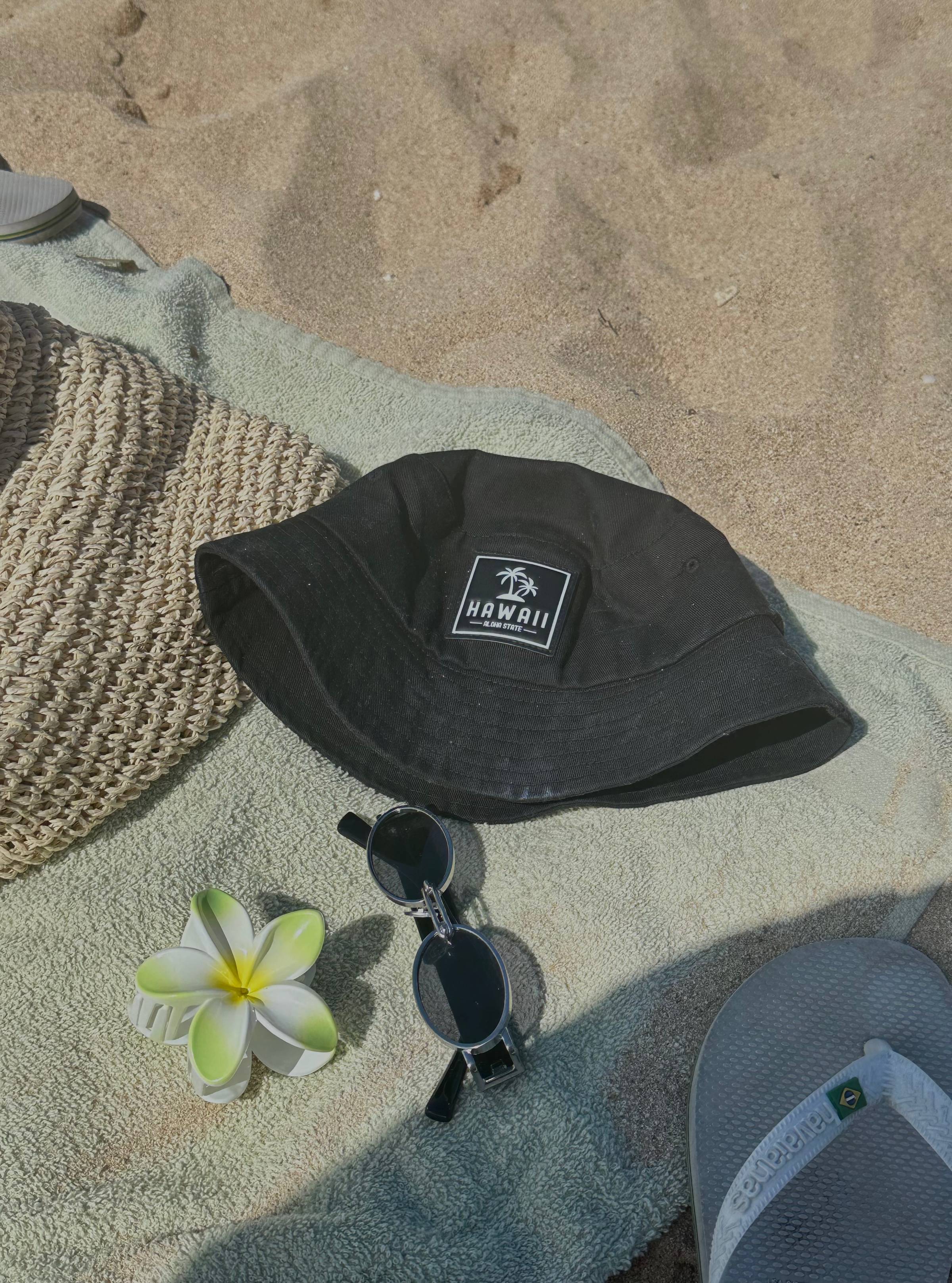 Image of a hat, bag, sunglasses and flower on a towel on the beach