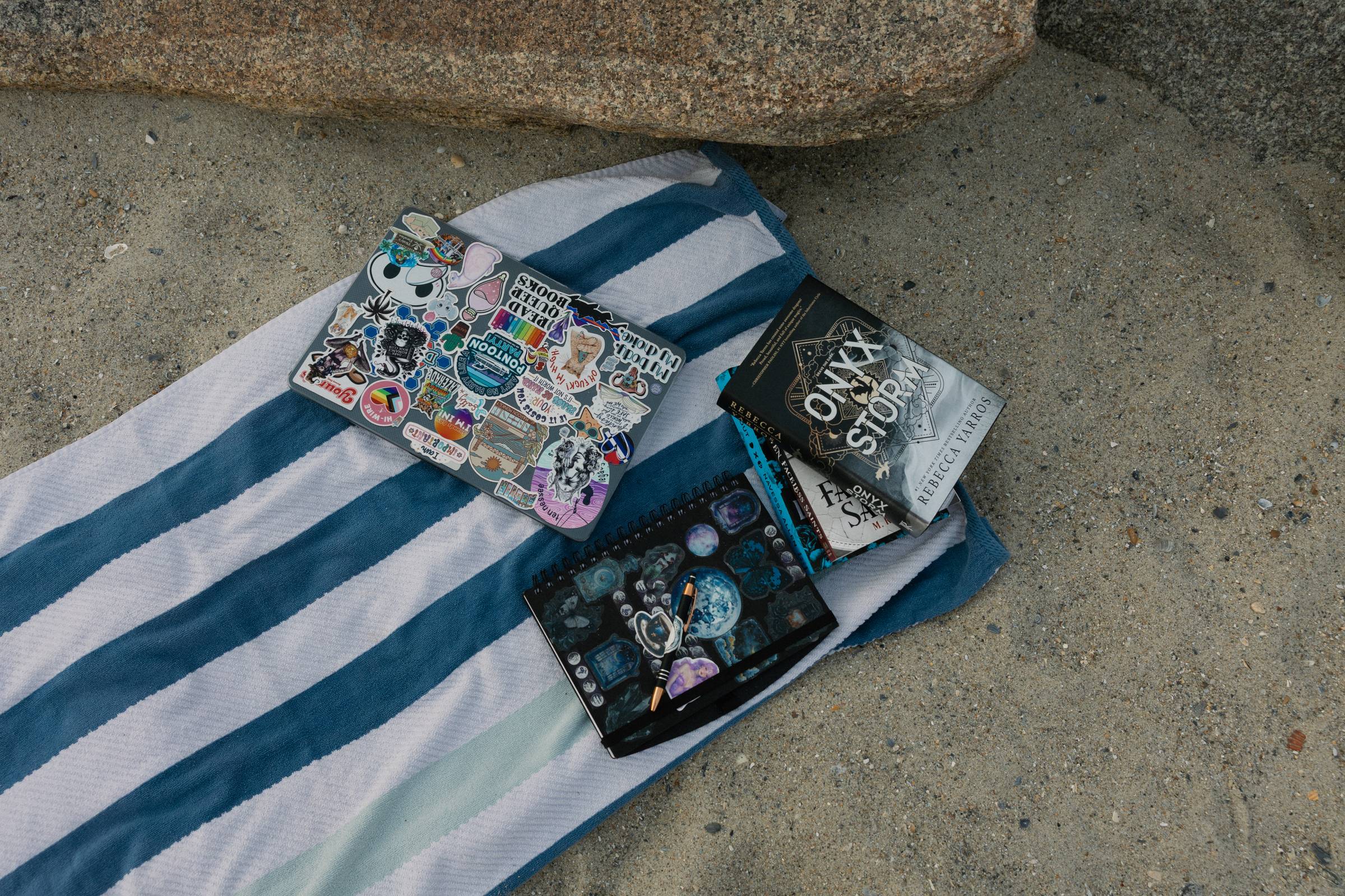 Image of Onyx Storm, my laptop, and journal on a towel in the sand
