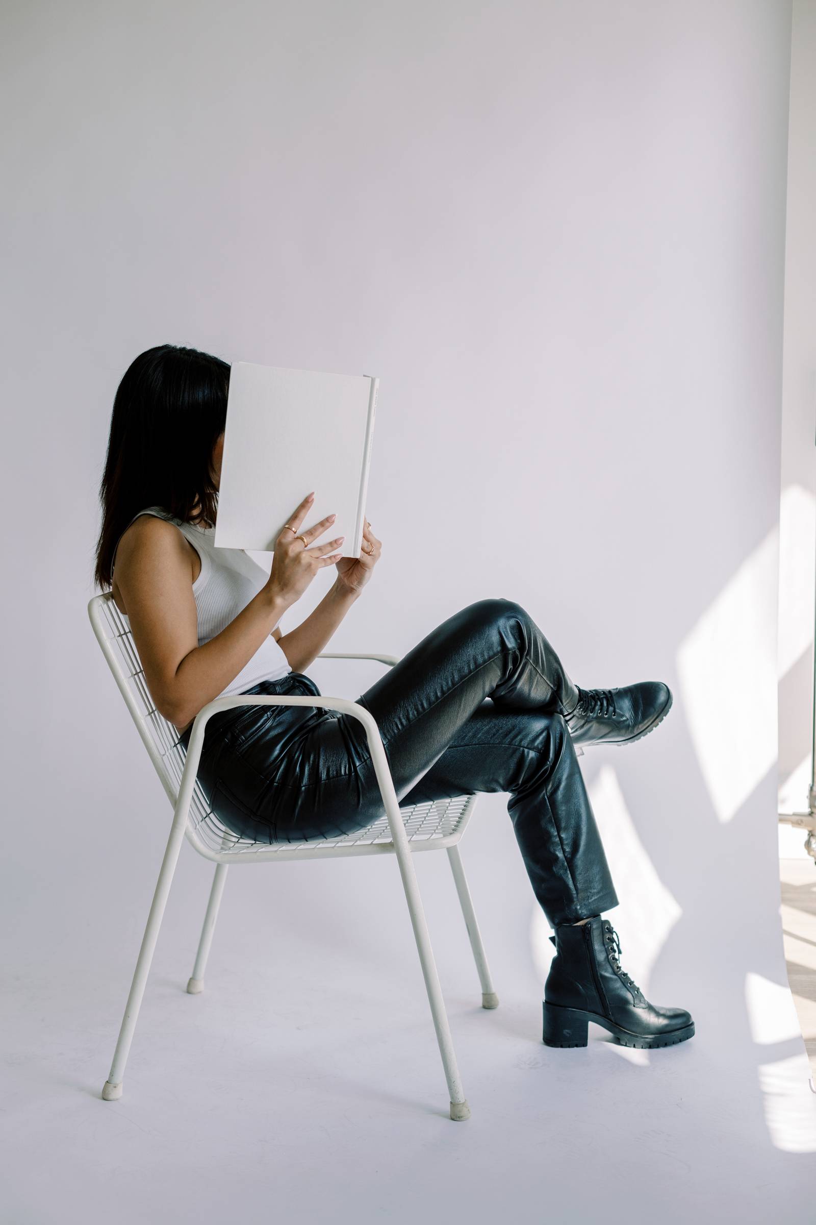 Image of a girl in black pants & a white top with her nose in a book