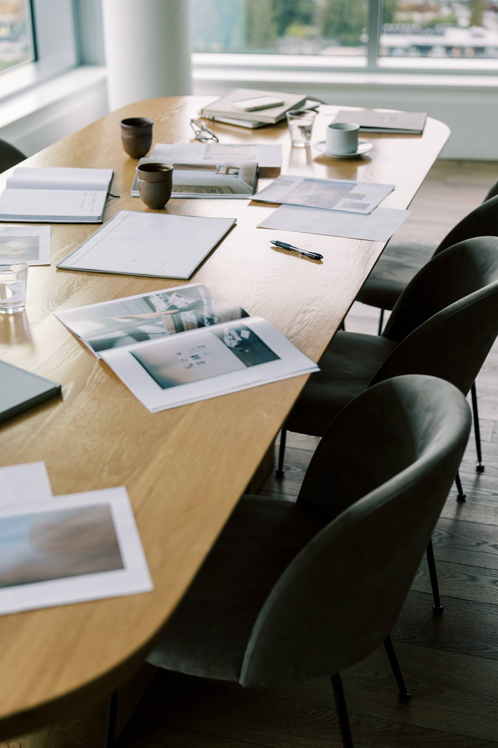 Image of magazines on a fancy corporate-esque table with black chairs tucked into it.