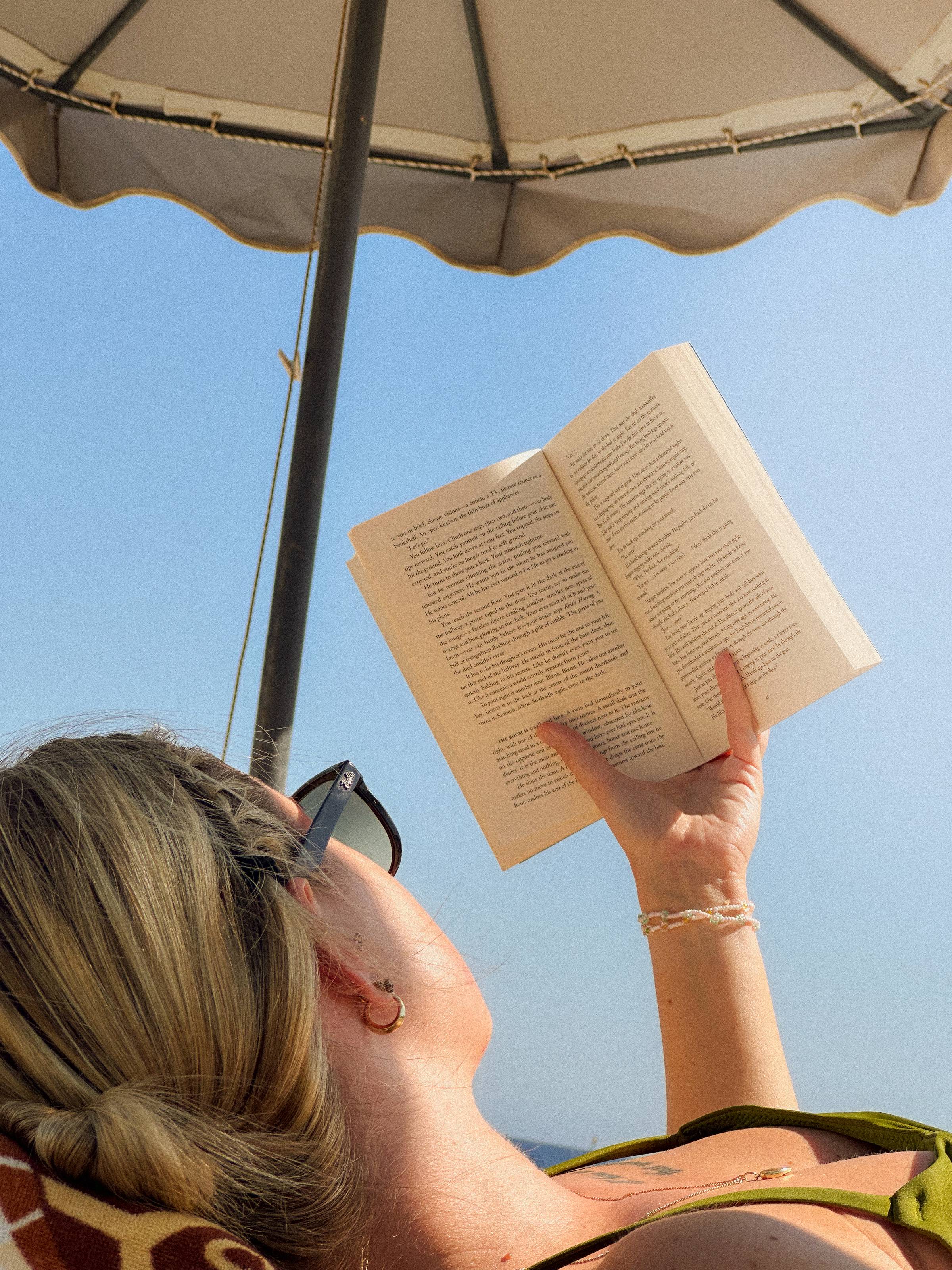 Image of a girl reading a book on the beach