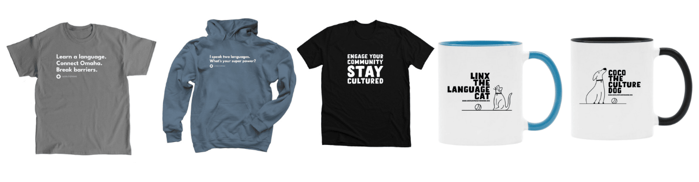 A row of five branded merchandise items from a language and culture organization. From left to right: Gray t-shirt with white text that reads, “Learn a language. Connect Omaha. Break barriers.” Blue hoodie with white text that says, “I speak two languages. What’s your super power?” Black t-shirt with bold white text that reads, “Engage your community. STAY CULTURED.” White mug with a blue handle and inner rim featuring an illustration of a cat and text that reads, “Linx the Language Cat.” White mug with a black handle and inner rim featuring an illustration of a dog and text that reads, “Coco the Culture Dog.”