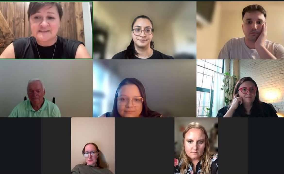 Image shows a group of people in a Zoom meeting. Tiles of different faces are laid out over a screen. 