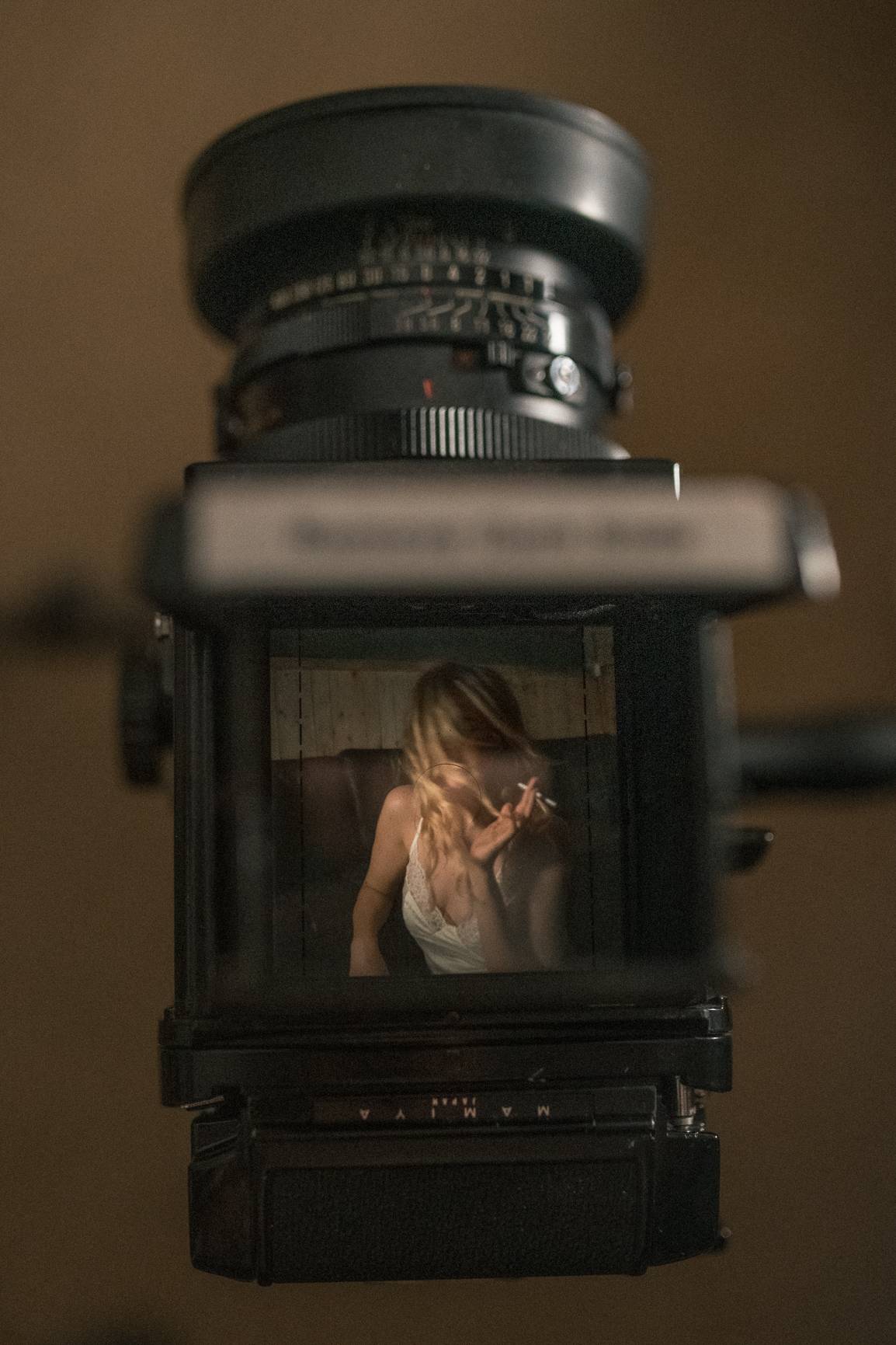 View through vintage medium format camera viewfinder showing artistic portrait composition in moody lighting.
