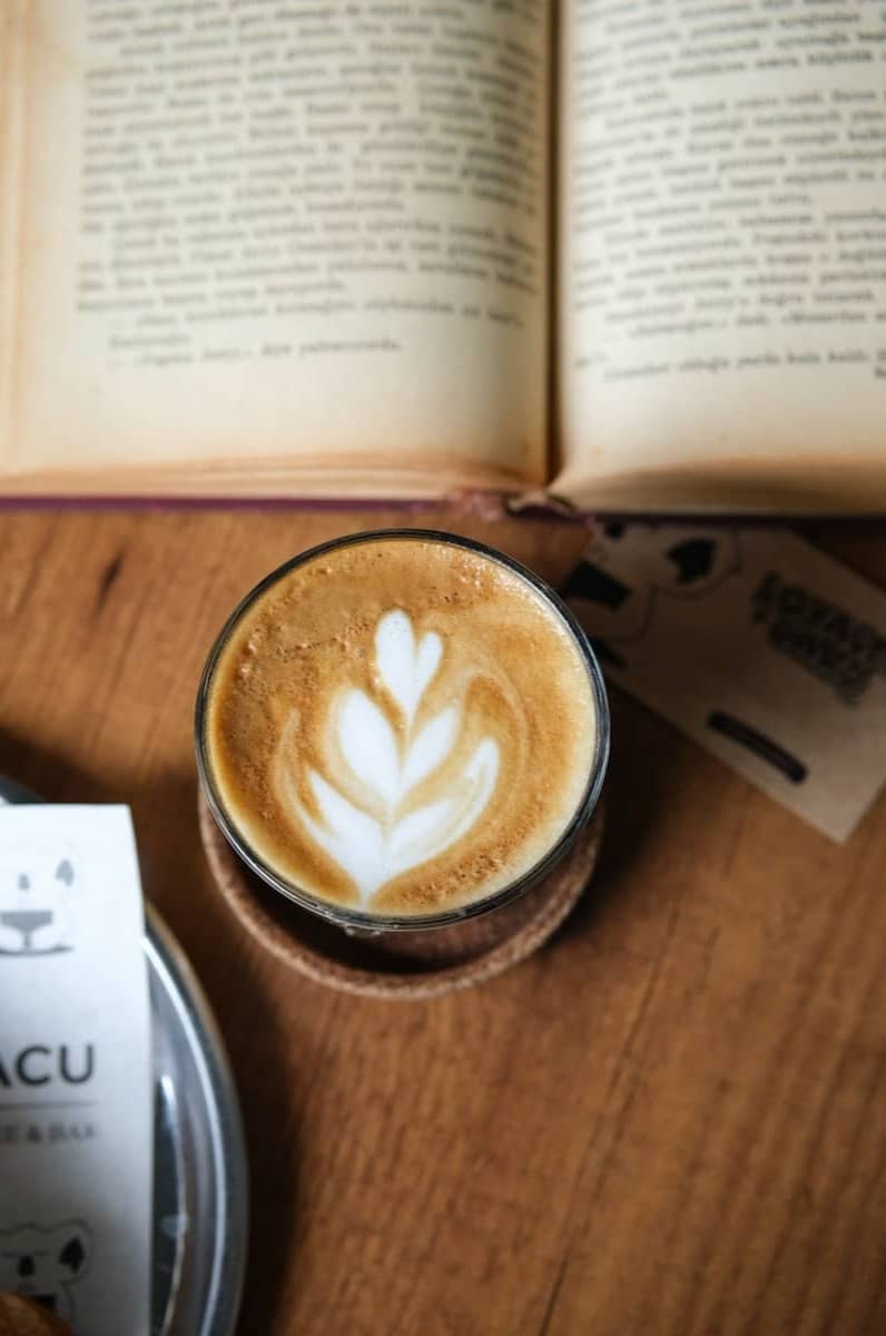 Latte art coffee with an open book on table