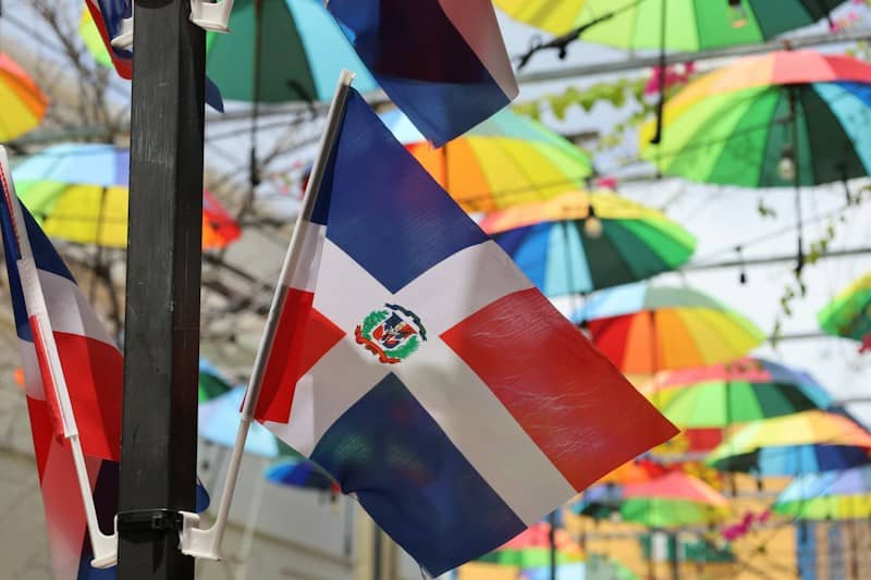 Dominican republic flag waving with colorful umbrellas in background.