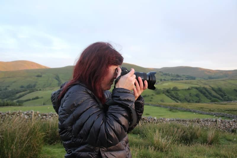 A woman photographs a scenic landscape.