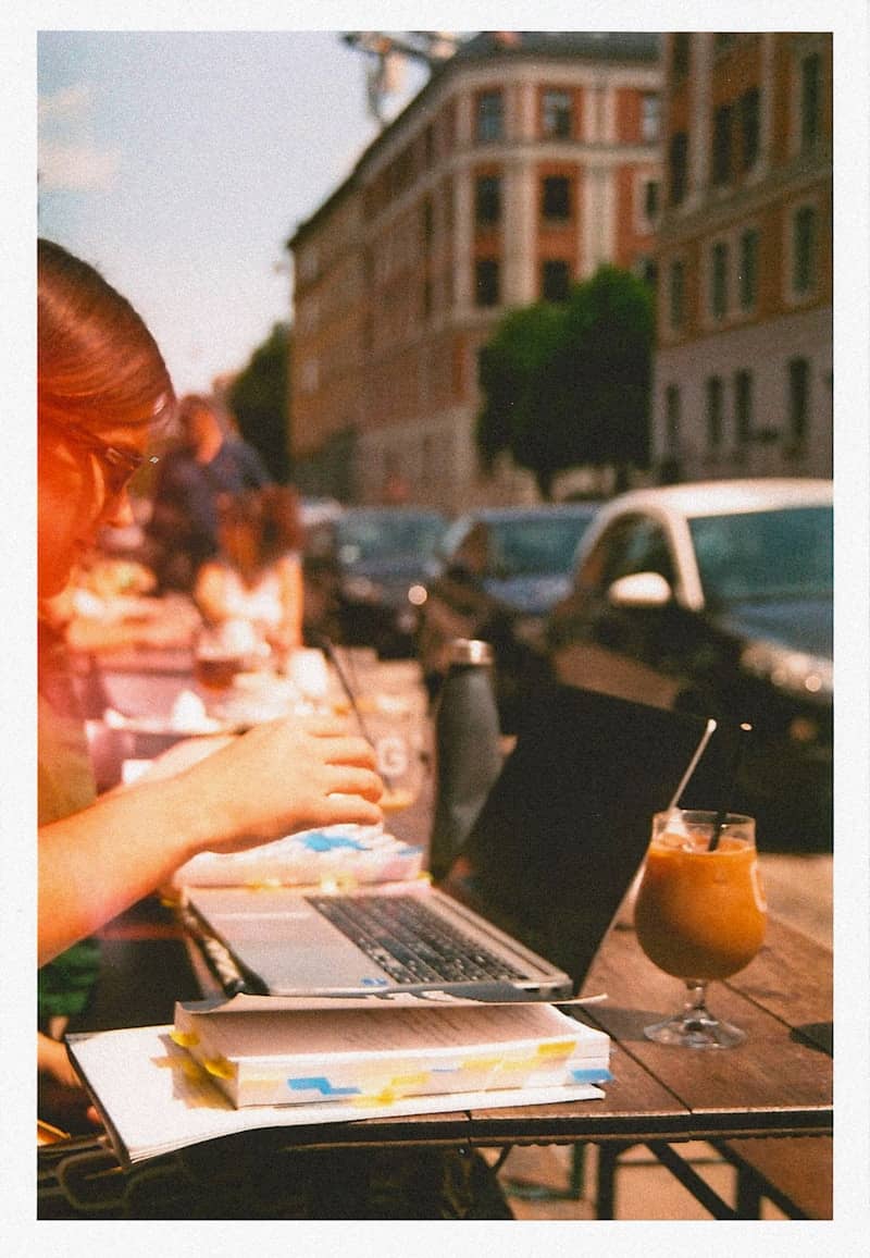 Woman works on laptop at an outdoor cafe.