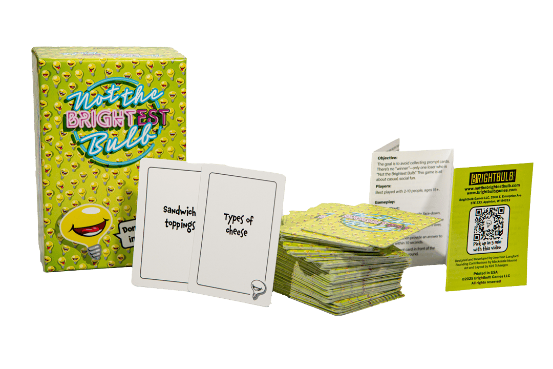 A full display of Not The Brightest Bulb, including the game box, a stack of prompt cards, two face-up cards reading 
