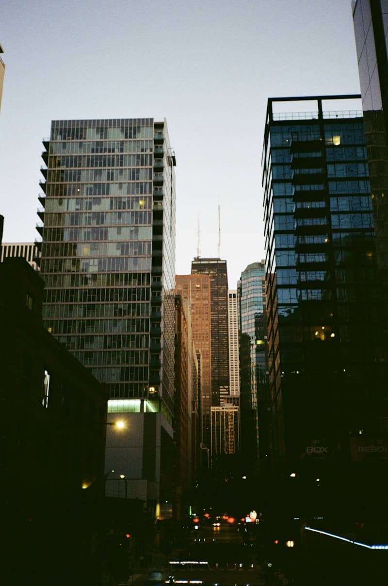 Modern skyscrapers line a city street at dusk.
