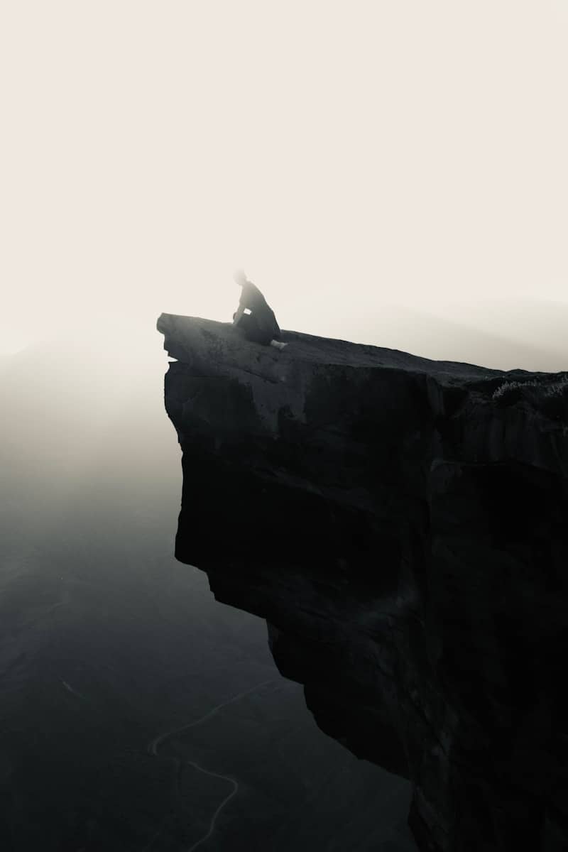 Silhouette of person meditating on a cliff edge.